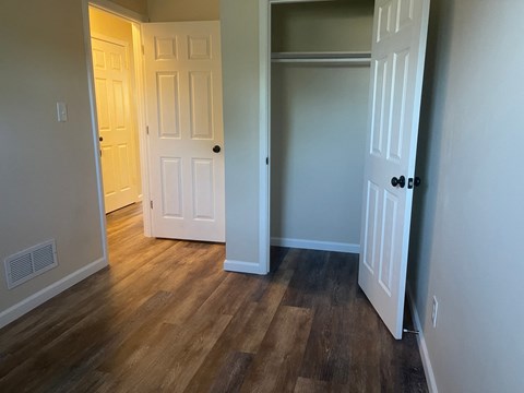 a living room with wood flooring and a door to a closet