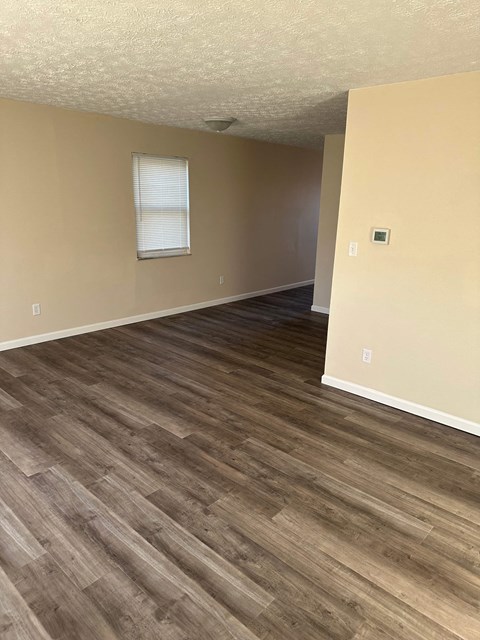 an empty living room with wooden floors and a window