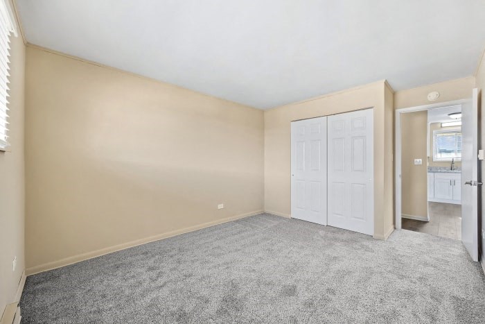 an empty living room with a white door and a closet