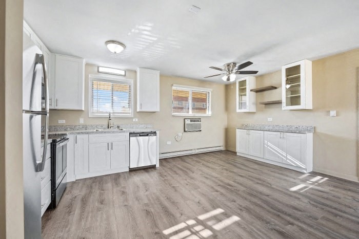 an empty kitchen with white cabinets and a refrigerator