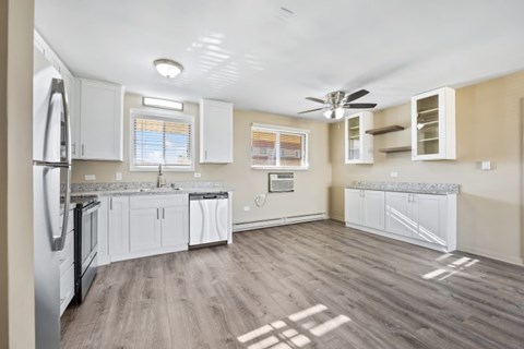 A kitchen with a refrigerator, cabinets, and a ceiling fan.