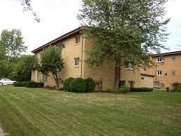 a large brick building with a green lawn and trees