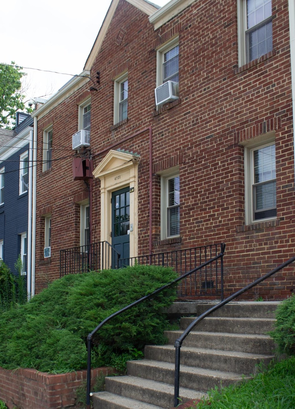 A red brick house with a black iron railing.
