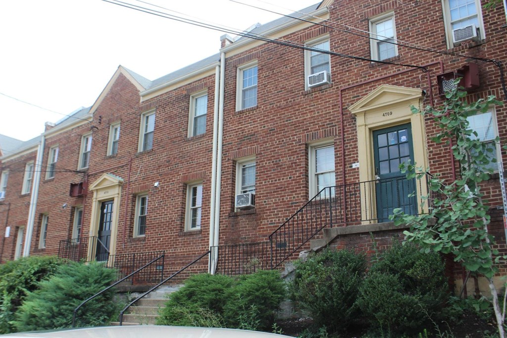 A red brick building with a yellow door and windows.