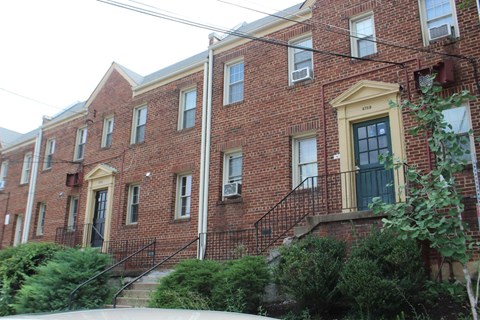 A red brick building with a yellow door and windows.