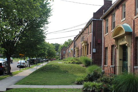 A row of red brick houses with green lawns in front.