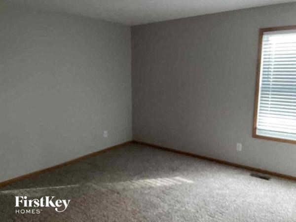 an empty bedroom with a window and a carpeted floor