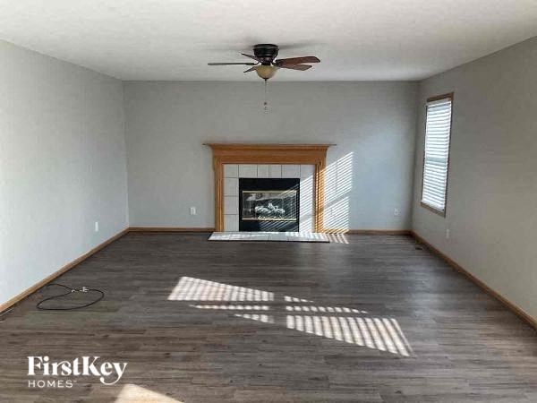 an empty living room with a ceiling fan and a fireplace