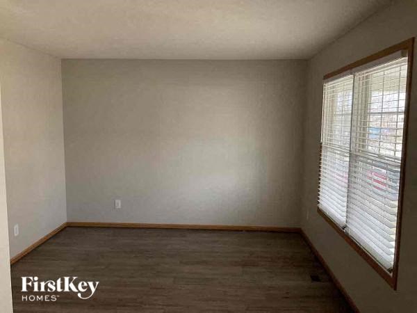 a empty room with a wood floor and two windows