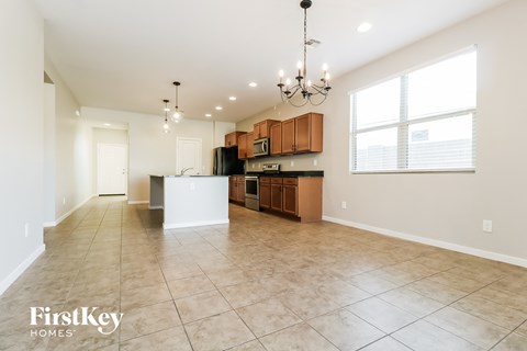 A spacious kitchen and living room with a chandelier and a dining table.