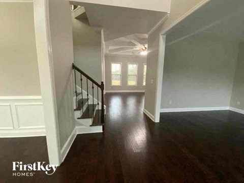 a hallway with a staircase and a hard wood floor