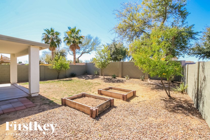 A backyard with a gravel area, a small tree, and a white building.
