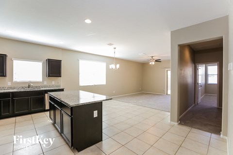 A kitchen with a black counter top and a tiled floor.