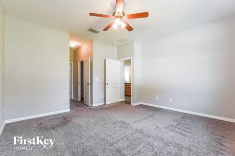 a spacious living room with carpet and a ceiling fan
