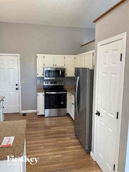 A kitchen with a refrigerator, oven, and microwave.