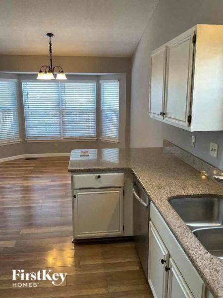 A kitchen with a wooden floor and white cabinets.