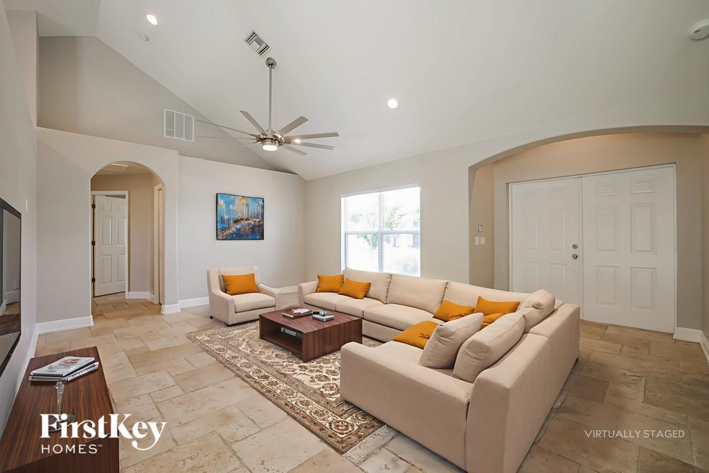 A living room with a couch, a coffee table, and a ceiling fan.
