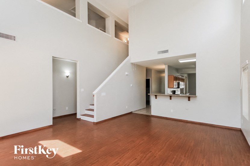 a living room with white walls and wood floors and a staircase