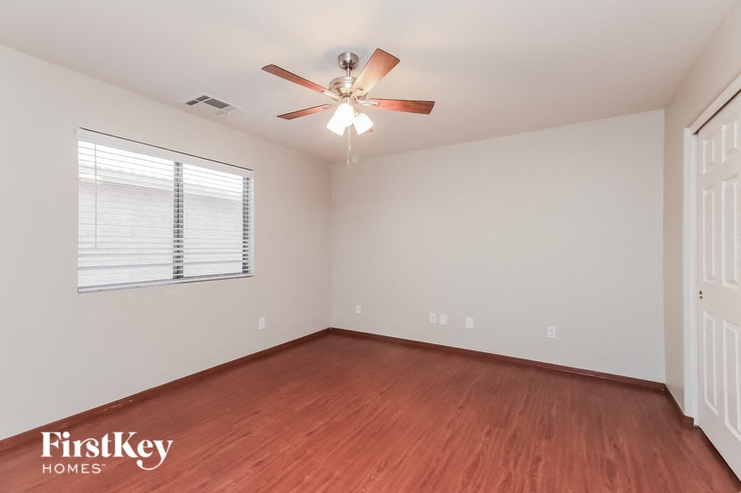 a bedroom with wood flooring and a ceiling fan
