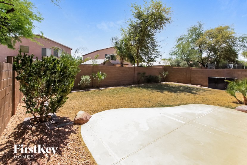 a yard with a concrete patio and a fence with a house in the background