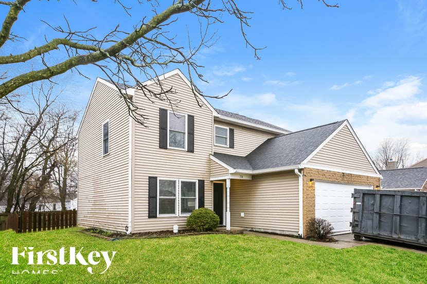 A house with a garage and a tree in front of it.