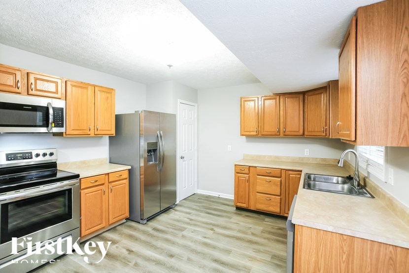A kitchen with wooden cabinets and a stainless steel refrigerator.