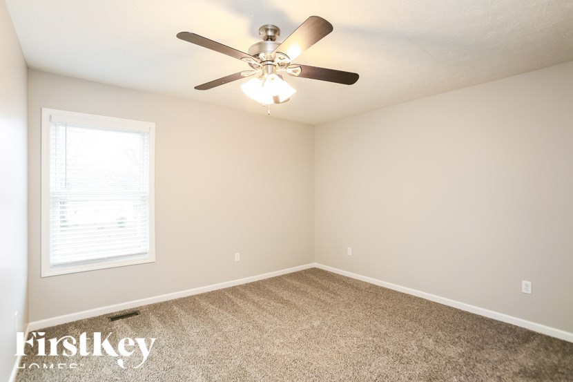 A room with a ceiling fan and carpeted floor.
