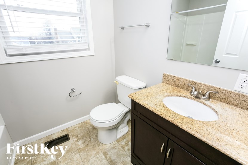 A bathroom with a toilet, sink, and mirror.