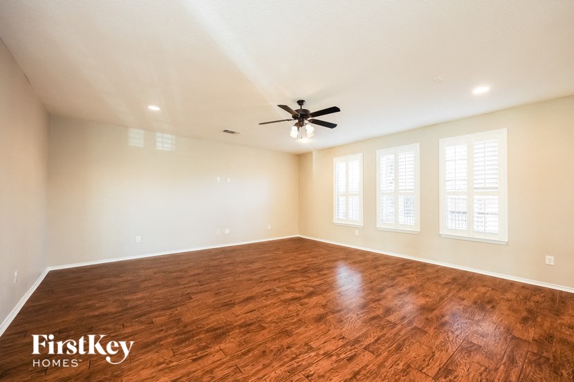 an empty living room with a ceiling fan and a wood floor