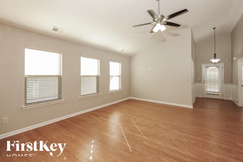 A spacious room with wooden flooring and a ceiling fan.
