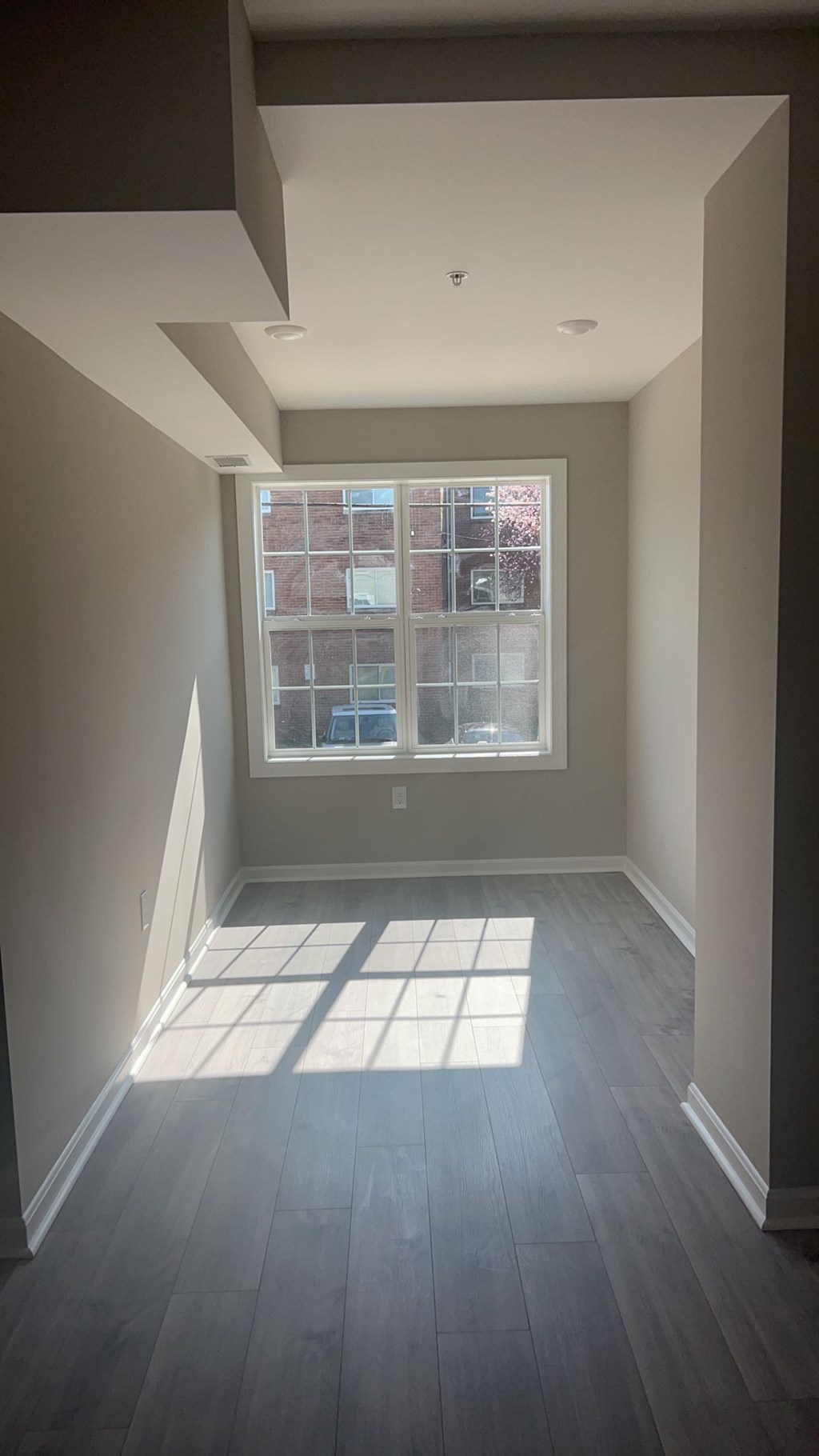 A room with a window and a wooden floor.