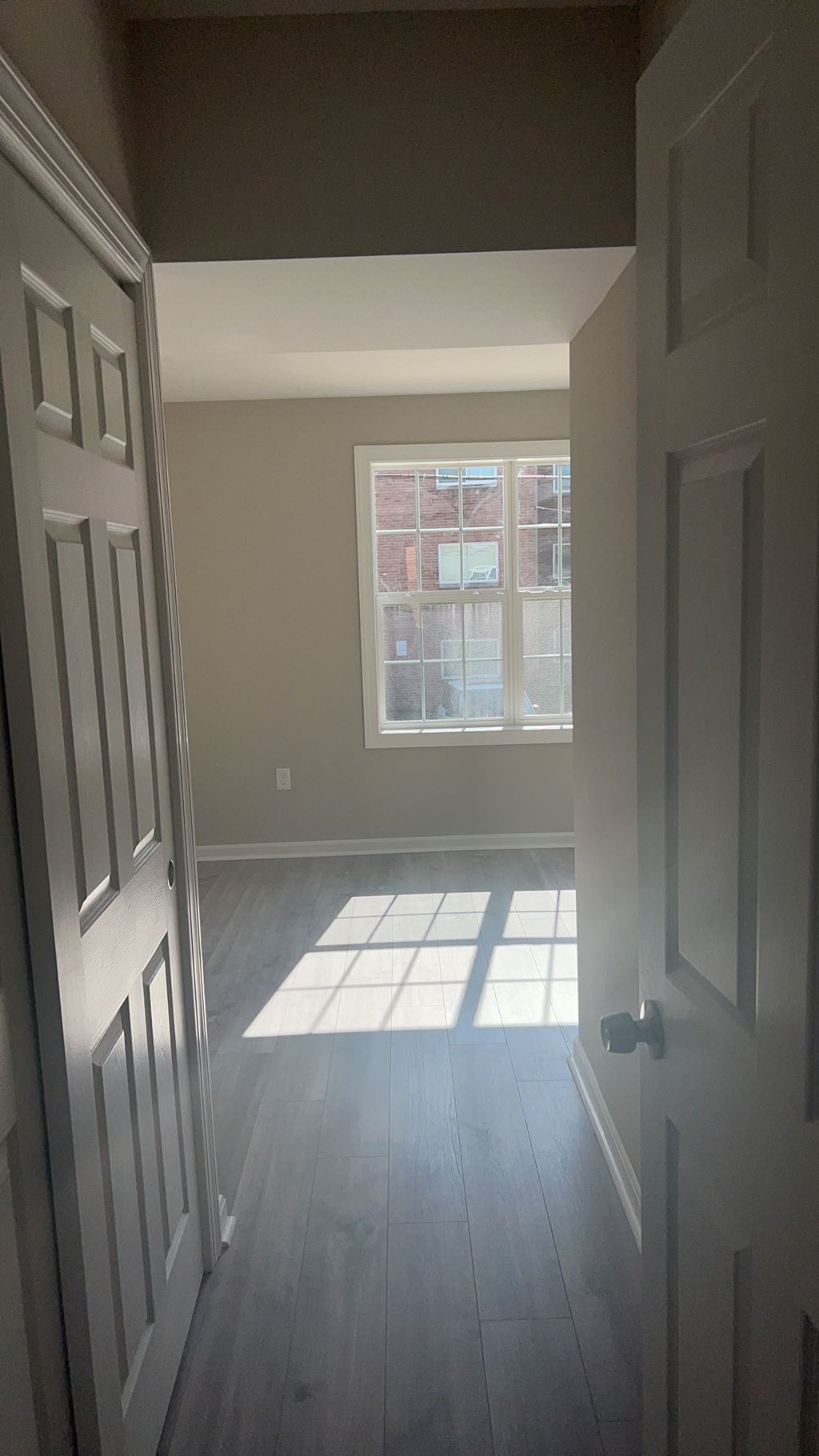 A hallway with a door on the left and a window on the right.