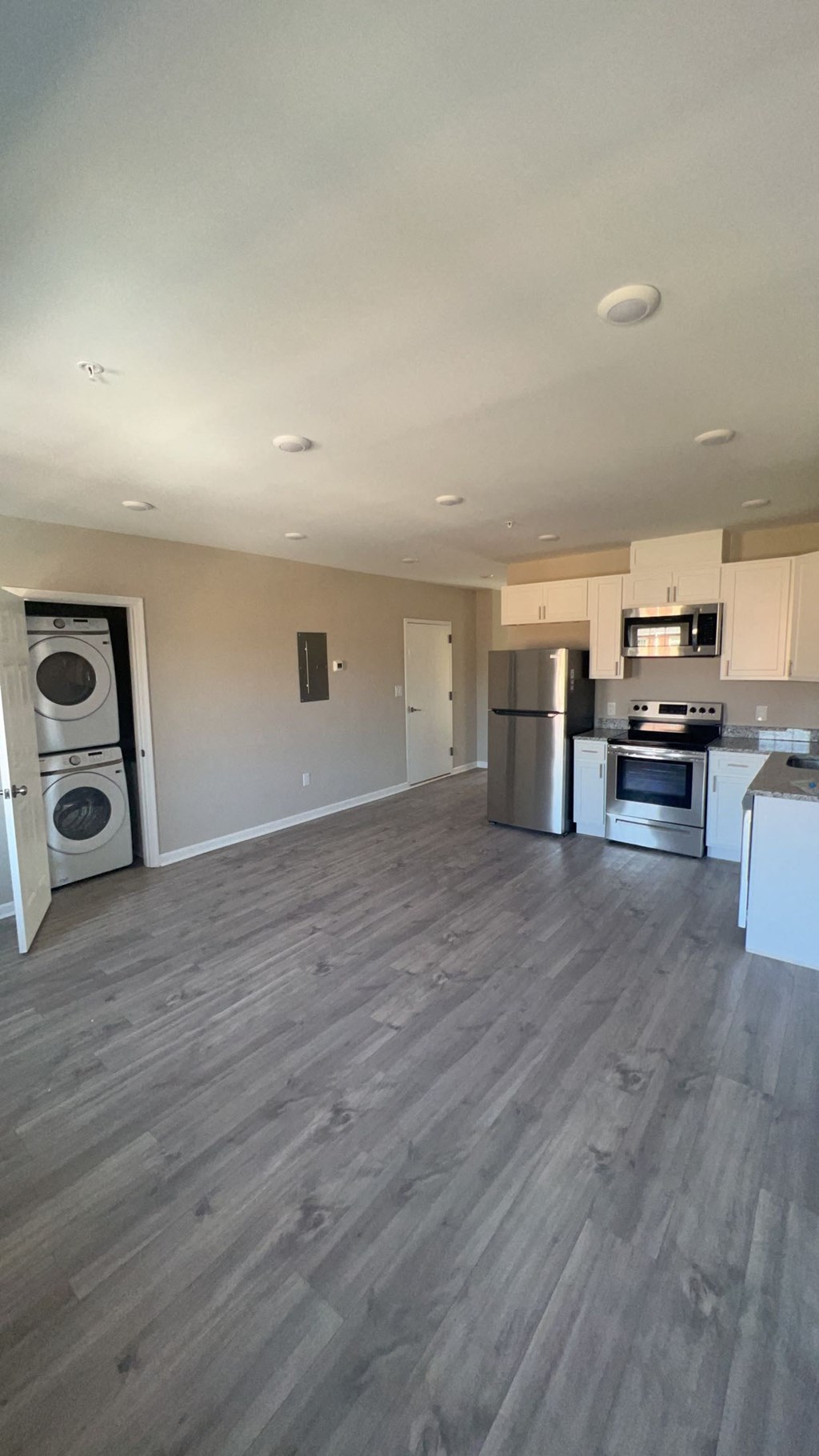 an empty living room and kitchen with wood floors