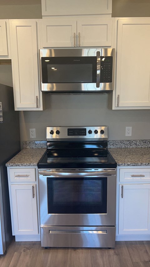 a kitchen with white cabinets and a stove and a microwave