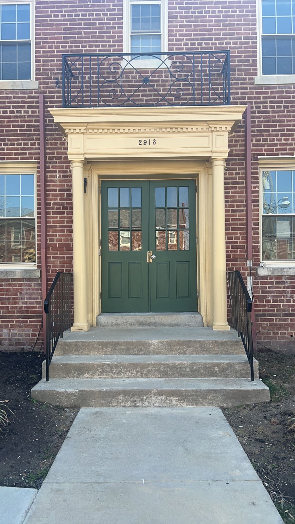 A green door with a black railing above it.