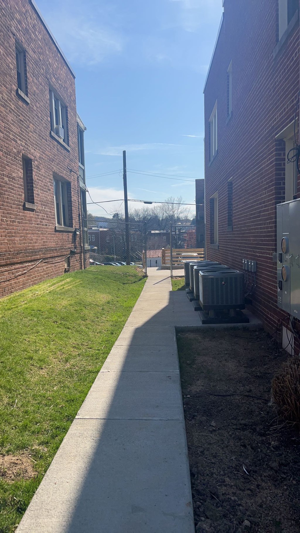 A long concrete walkway leads between two red brick buildings.