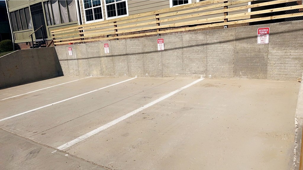 A parking lot with a no parking sign on the wall.