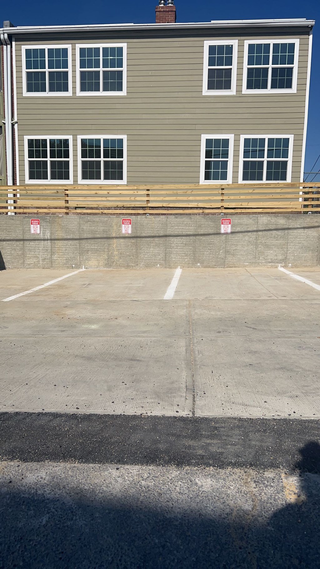 A grey building with a parking lot in front.