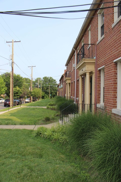 A row of red brick houses with green grass in front.