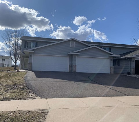 a blue and white house with a driveway and a cloudy sky