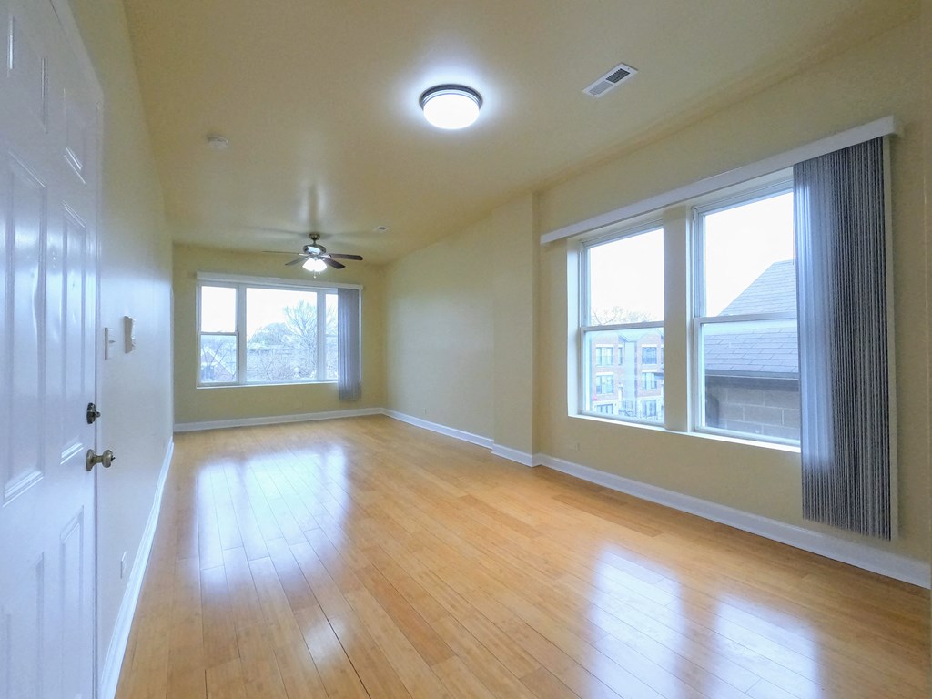 an empty living room with a ceiling fan and windows
