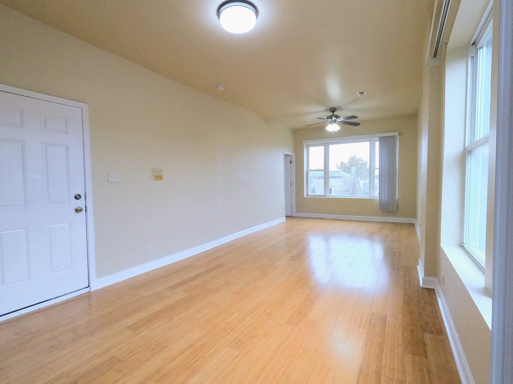 an empty living room with wood floors and a ceiling fan