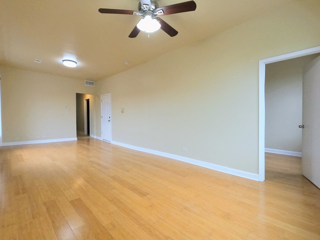 an empty living room with wood floors and a ceiling fan