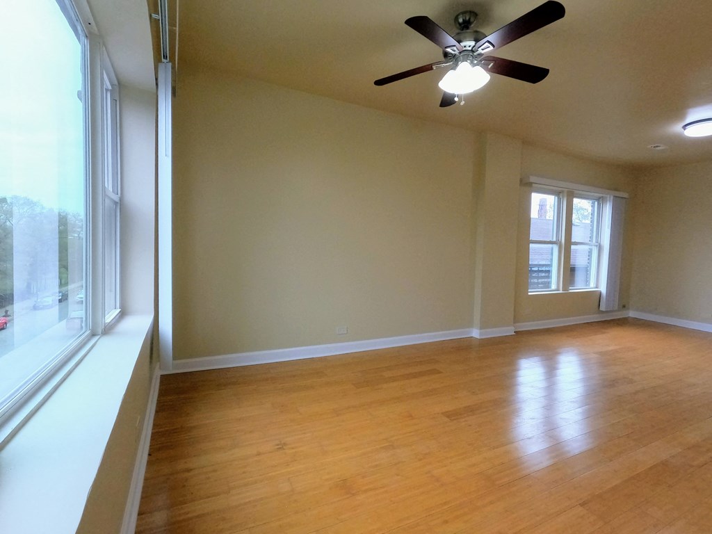 an empty living room with a ceiling fan and a large window