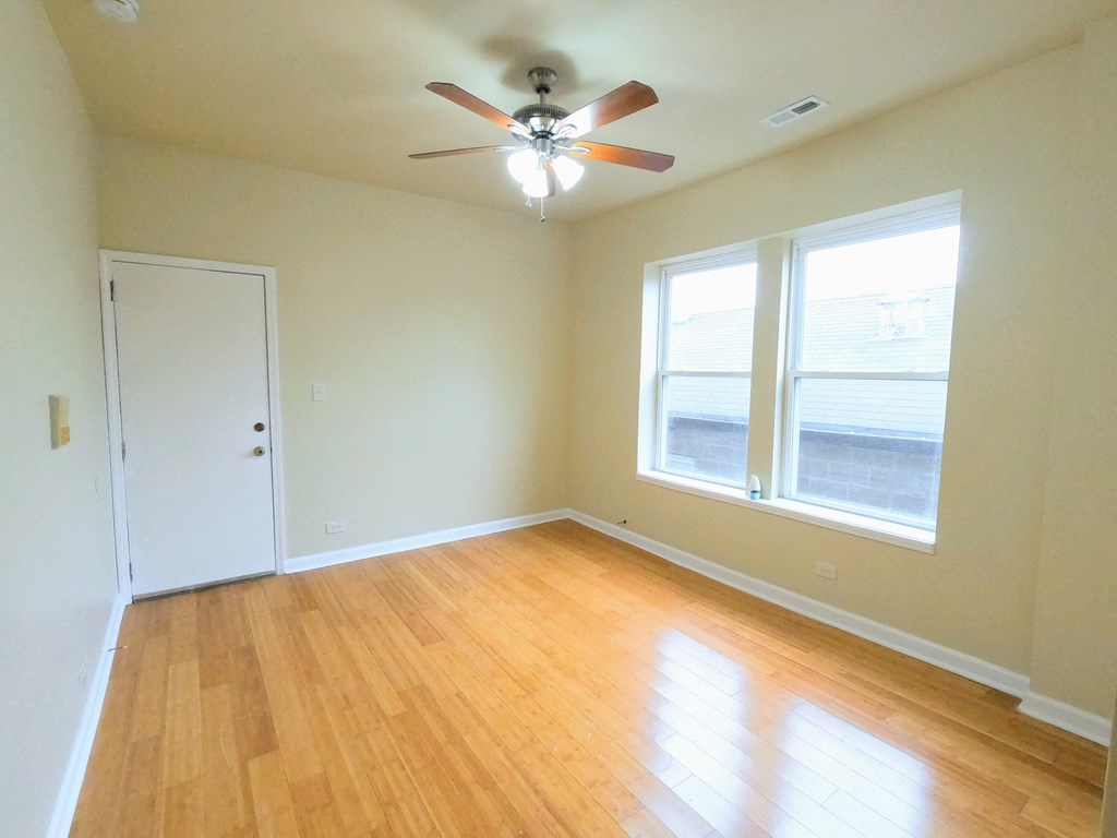an empty living room with a ceiling fan and two windows