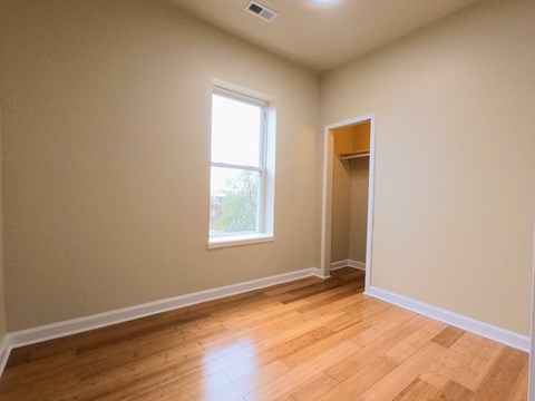 an empty living room with a window and wooden floors