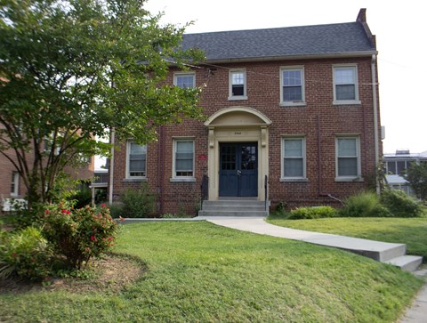A red brick house with a black front door and a small porch.