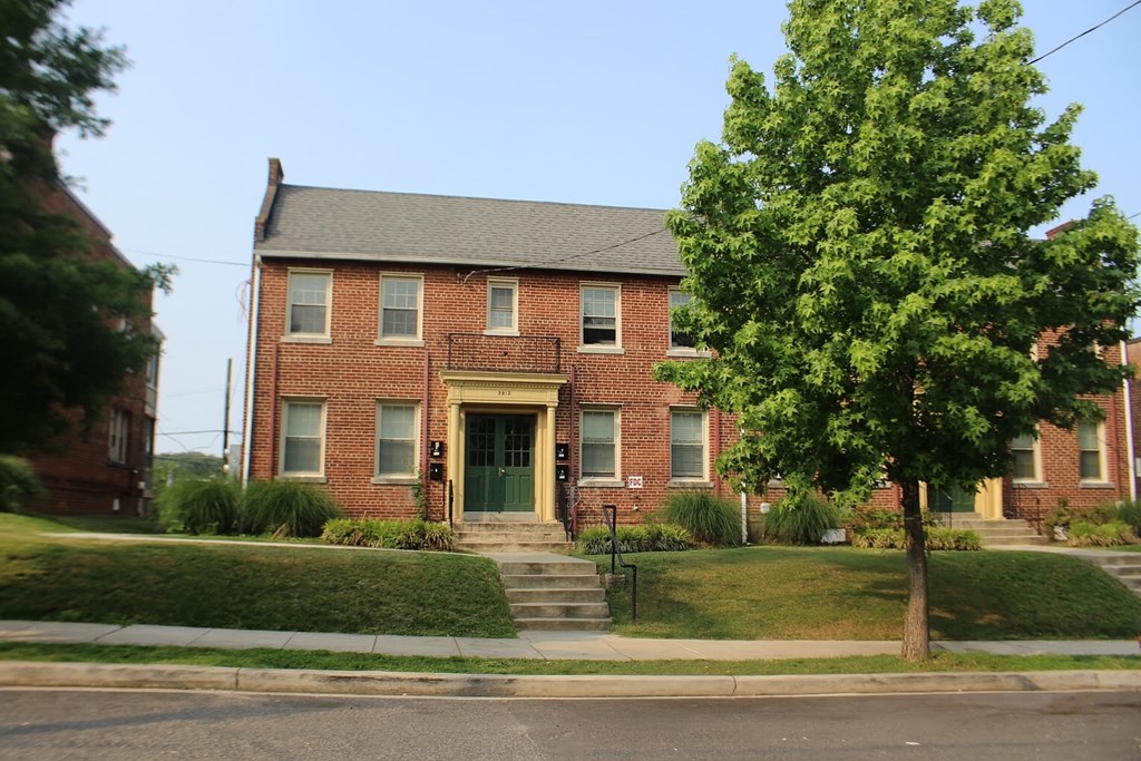 A red brick house with a green tree in front.