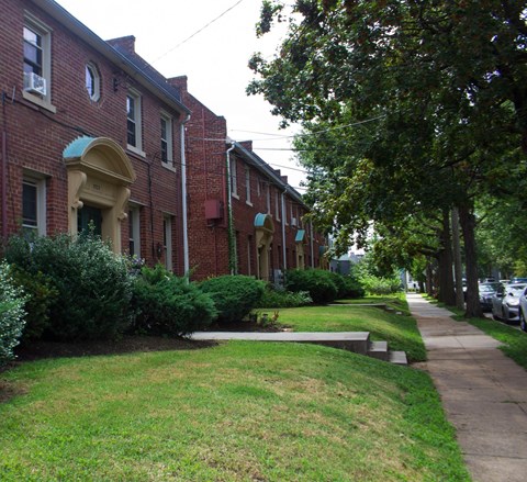 A row of red brick houses with green lawns in front.