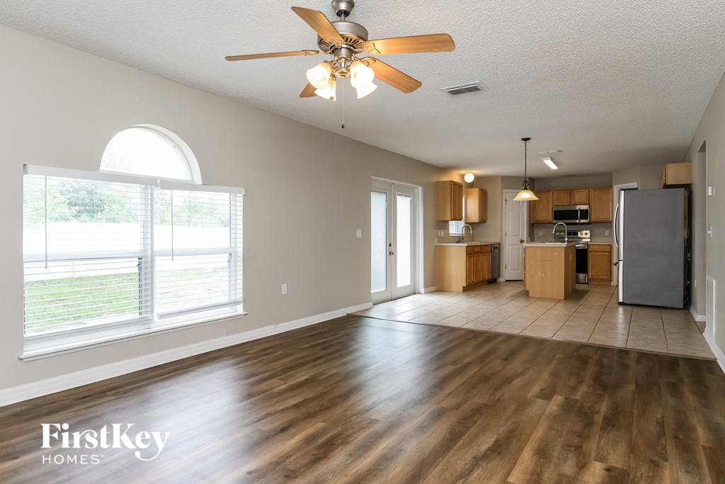 A spacious room with wooden floors and a ceiling fan.